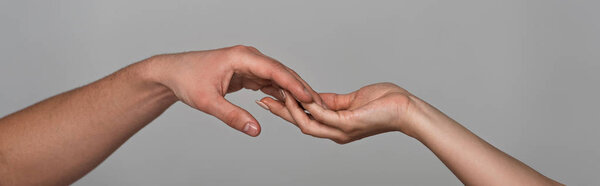 panoramic shot of young couple touching hands isolated on grey
