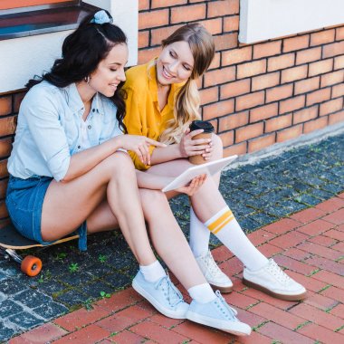 mutlu kadın arkadaşı ile penny kurulu üzerinde otururken dijital tablet parmak ile işaret 