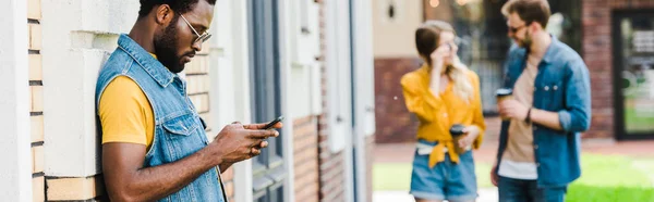 外のスマートフォンを使用してサングラスでハンサムなアフリカ系アメリカ人男性のパノラマショット — ストック写真