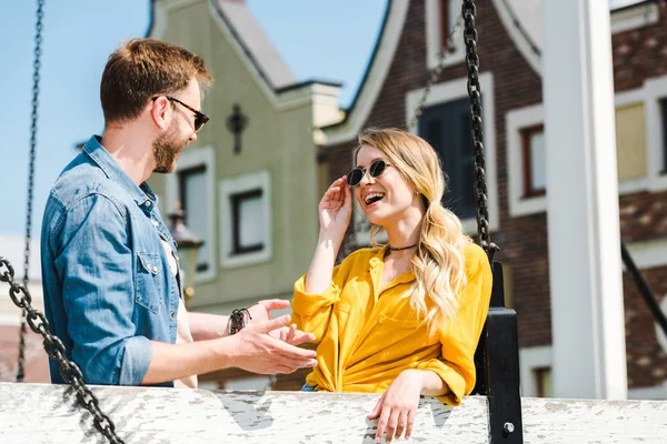 Vrolijke Vrouw Aanraken Zonnebril Kijken Naar Man Buiten — Stockfoto