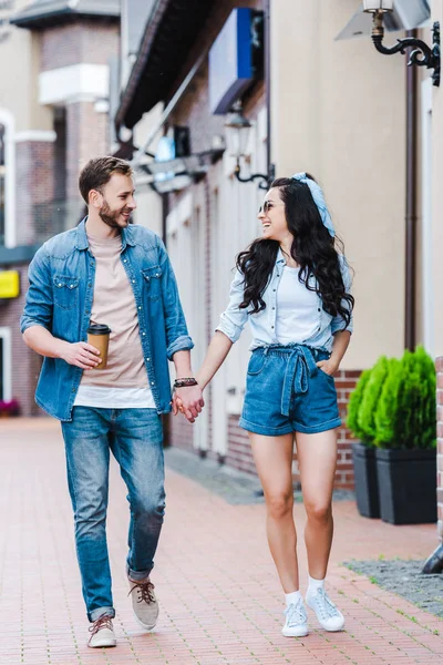 ポケットの中に手を持つ幸せな女性は 男性と手をつないで歩いて — ストック写真