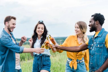 mutlu çok kültürlü erkek ve kadın bira ile şişe clinking 