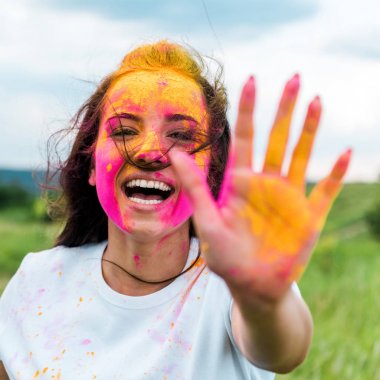 yüz ve ellerde pembe ve sarı holi boya ile neşeli kadının seçici odak