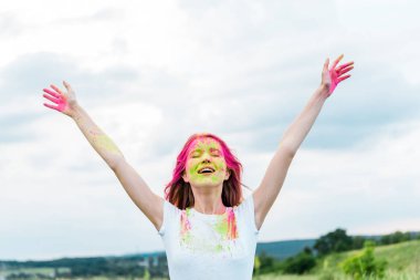 kapalı gözlü genç kadın, uzanmış ellerüzerinde pembe ve yeşil holi boya 