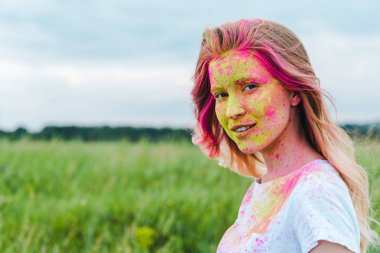  yüzünde yeşil ve pembe holi boya ile mutlu genç kadın 