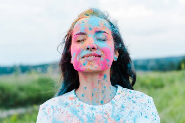 kapalı gözleri ve yüzünde renkli holi boyalar ile pozitif kadın 