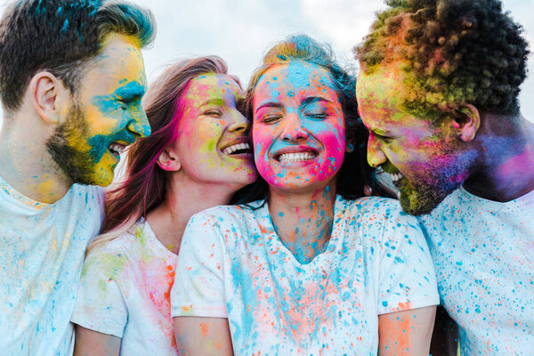 happy african american man near cheerful friends with holi paints on faces 