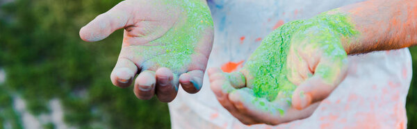 panoramic shot of young man with holi paints on hands 