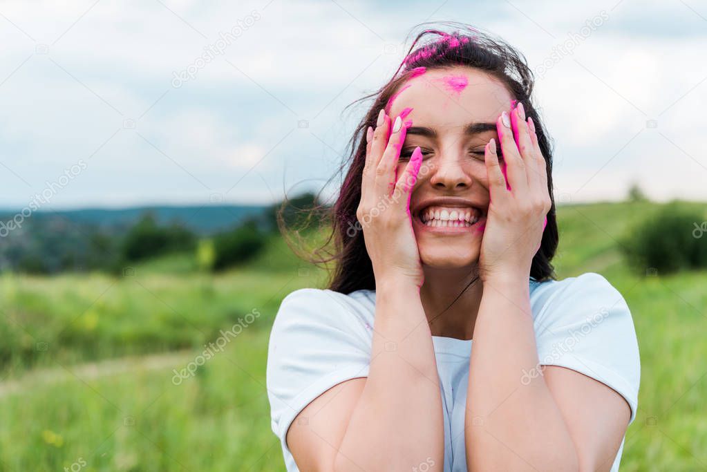 happy young woman standing with closed eyes and covering face with hands 