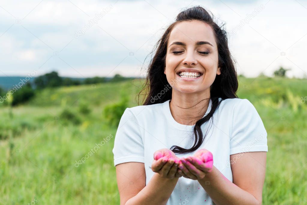 happy woman standing and holding pink powder in hands
