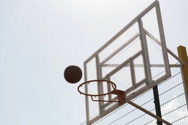 güneşli bir günde gökyüzü altında top ve basketbol potası