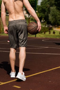 güneşli bir günde basketbol sahasında topu ile basketbolcu kısmi görünümü