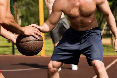 basketbol sahasında basketbol oynayan gömleksiz sporcuların kısmi görünümü