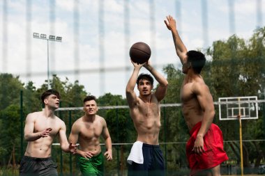 basketbol sahasında basketbol oynayan gömleksiz sporcuların seçici odak