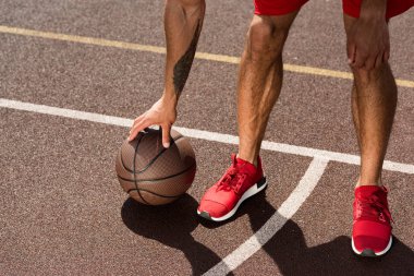 basketbol sahasında topu ile kırmızı spor ayakkabılı sporcu nun kırpılmış görünümü