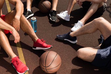 basketbol sahasında oturan top ve spor şişesi ile basketbol oyuncuları kısmi görünümü