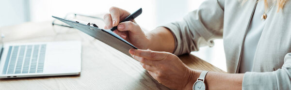 панорамный снимок вербовщика, пишущего на планшете в офисе
 