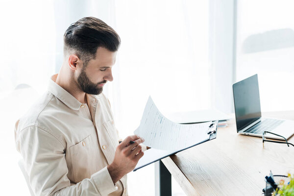 Hombre Barbudo Guapo Mirando Papel Mientras Sostiene Portapapeles — Foto de Stock