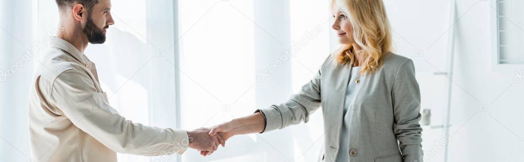 panoramic shot of recruiter and handsome employee shaking hands 