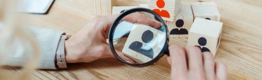 panoramic shot of recruiter holding magnifier near wooden cube  clipart