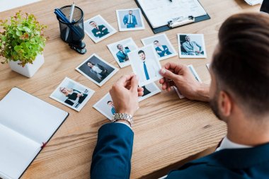 selective focus of recruiter choosing while holding photo near wooden table  clipart