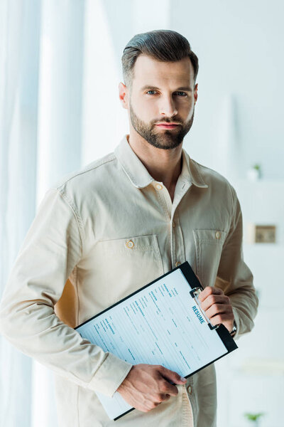 handsome bearded man holding clipboard and looking at camera 