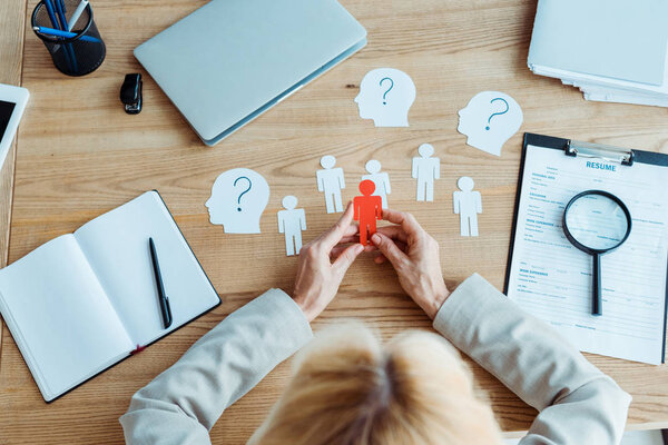 top view of woman holding paper shape near blank notebook on table 