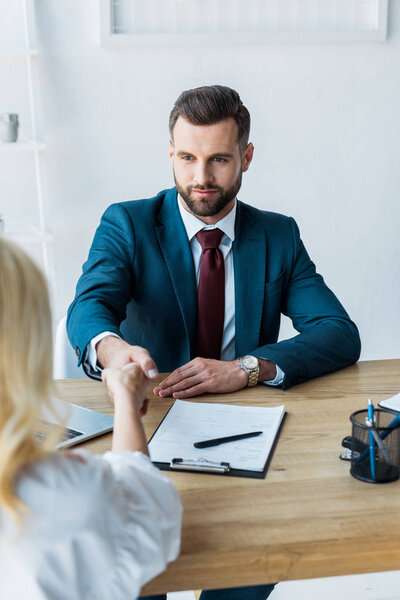 selective focus of employee and handsome recruiter shaking hands 