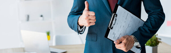 panoramic shot of recruiter standing and holding clipboard with resume letters while showing thumb up