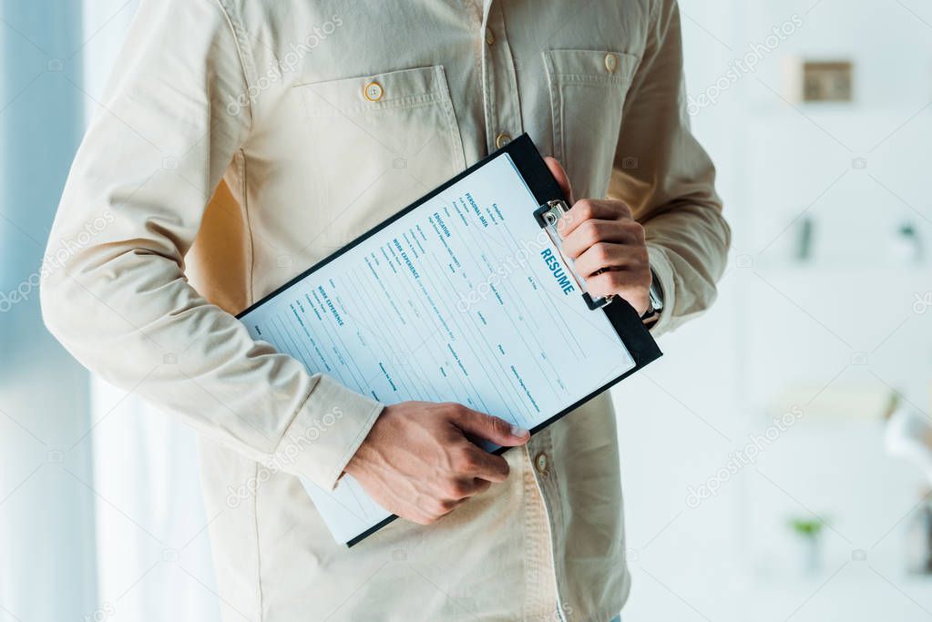 cropped view of man holding clipboard while standing in office 