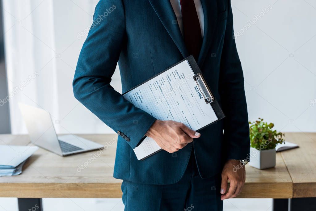 cropped view of man standing and holding clipboard with resume letters 