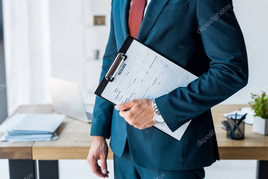 cropped view of recruiter standing and holding clipboard with resume letters 