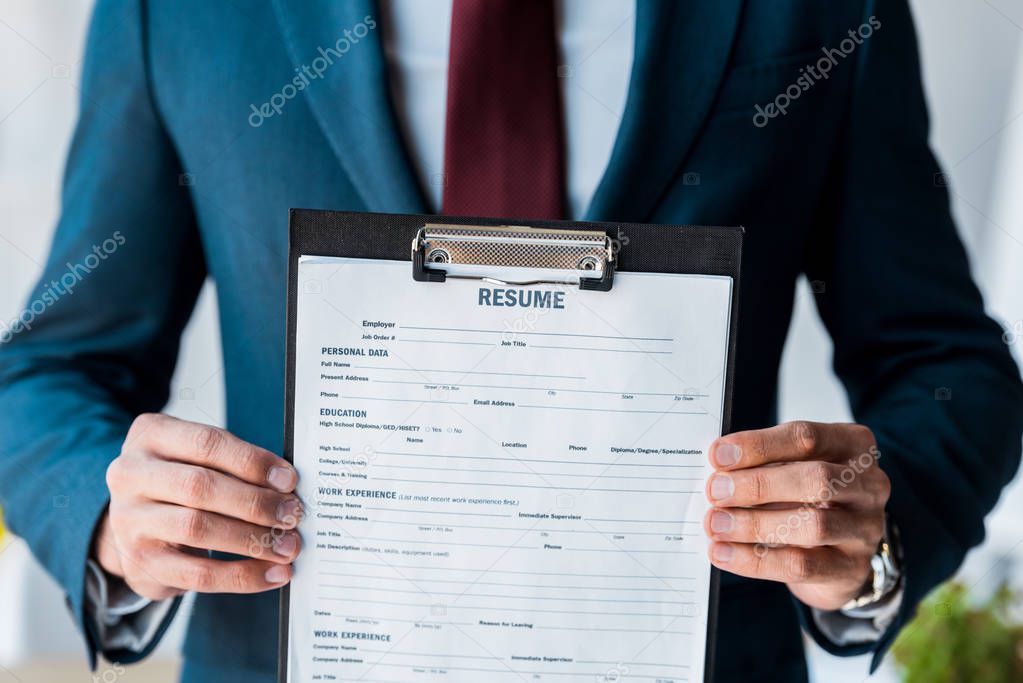 selective focus of clipboard with resume lettering in hands of man 
