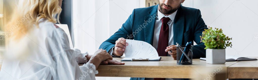 panoramic shot of bearded recruiter sitting near blonde employee 