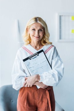 ofiste özgeçmiş ile pano tutan neşeli sarışın kadın 