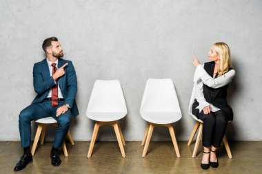 beyaz sandalyelerde otururken parmakları ile işaret yakışıklı sakallı adam ve çekici sarışın kadın 