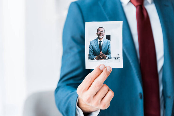 cropped view of recruiter touching photo with african american man in glasses 