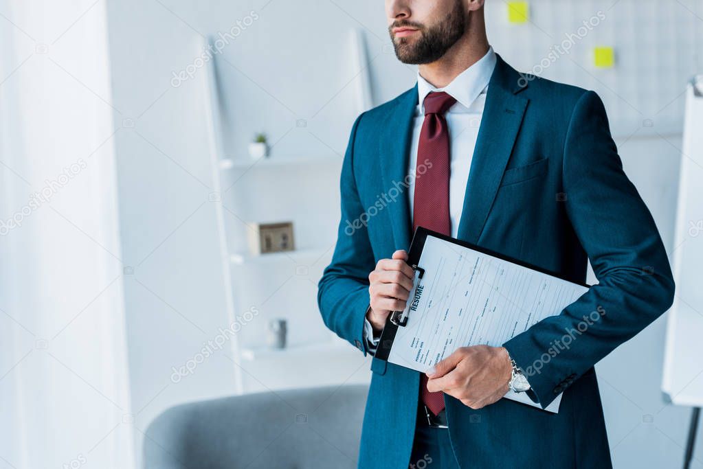 cropped view of bearded man holding clipboard with resume letters 