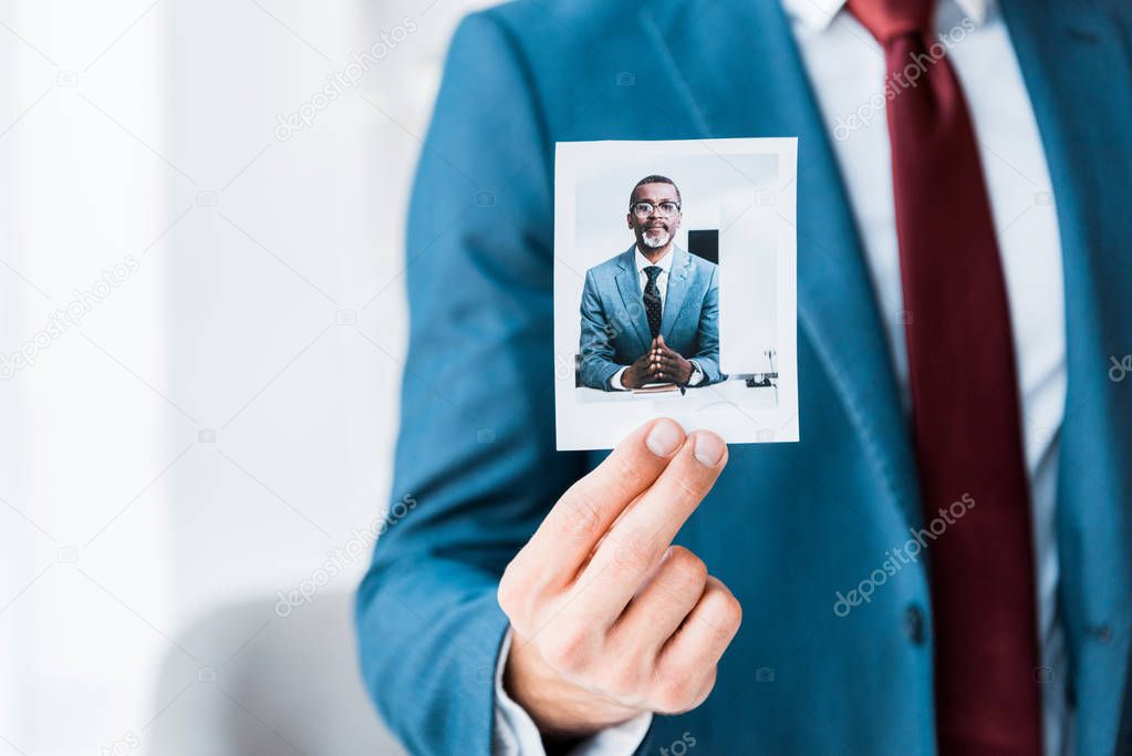 cropped view of recruiter touching photo with african american man in glasses 