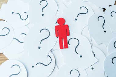 red human shape near question marks on paper with human heads on wooden table  clipart