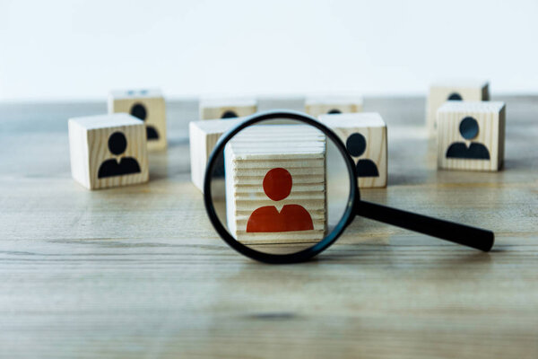 selective focus of magnifying glass near cubes on wooden desk 