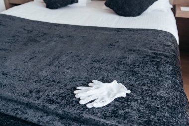 white gloves on bed with cushions in hotel room clipart