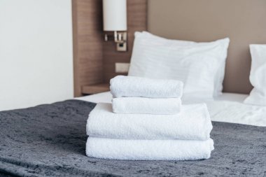 folded white towels on bed in hotel room clipart