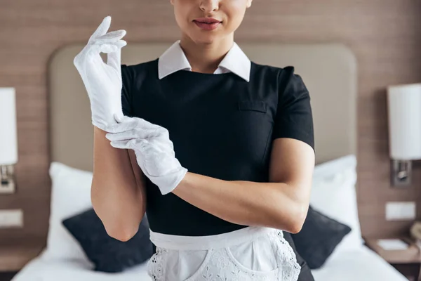 Vista Parcial Criada Sonriente Delantal Blanco Poniéndose Guantes Habitación Hotel — Foto de Stock