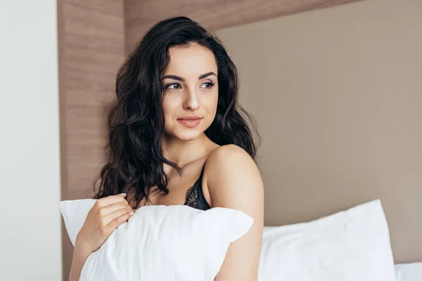性感的年轻女子在内衣抱着白色枕头在卧室 — 图库照片
