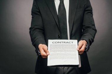 koyu arka plan üzerinde sözleşme gösteren Afrikalı Amerikalı işadamı nın kırpılmış görünümü