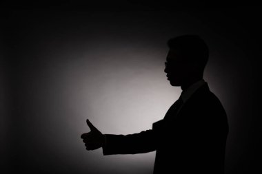 arka ışık ile başparmak gösteren işadamısiyah siluet yan görünümü