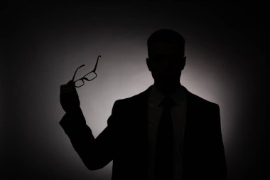 arka ışık ile gözlük tutan işadamının siyah siluet