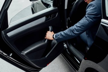 takım elbiseli araba kapısı kapatan Afrikalı Amerikalı adam kırpılmış görünümü