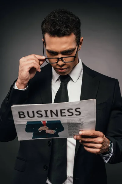 暗い背景にビジネス新聞を読んで眼鏡でアフリカ系アメリカ人のビジネスマン — ストック写真